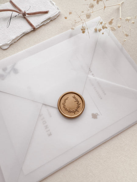 Delicate botanical wreath gold wax seal on a vellum wedding invitation envelope