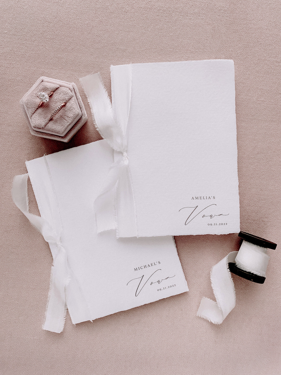 white handmade paper vow books personalized with the couple's names and wedding date, tied in white silk ribbons 