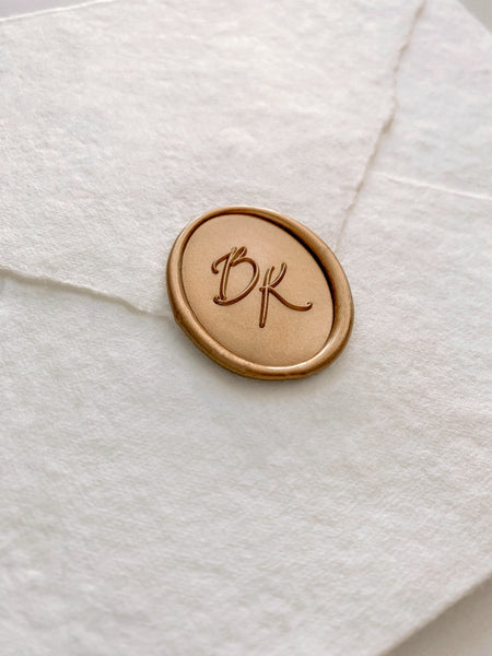 Calligraphy script monogram oval wax seal in gold on handmade paper envelope_side angle