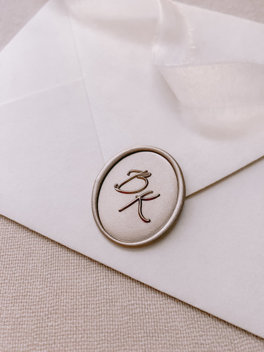 Calligraphy script monogram oval mocha custom wax seal on white paper envelope