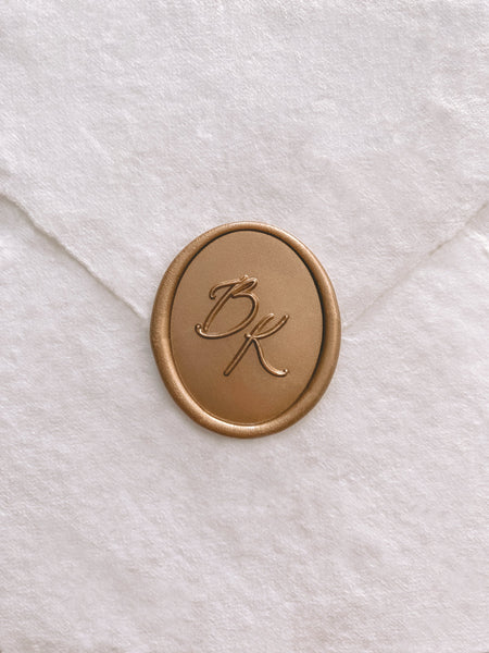 Calligraphy script monogram oval wax seal in gold on handmade paper envelope_front angle