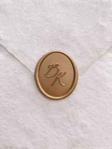 Calligraphy script monogram oval gold custom wax seal on beige handmade paper envelope
