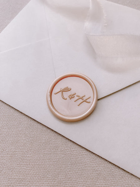 Calligraphy script monogram round light pink custom wax seal in nude pearl on white paper envelope