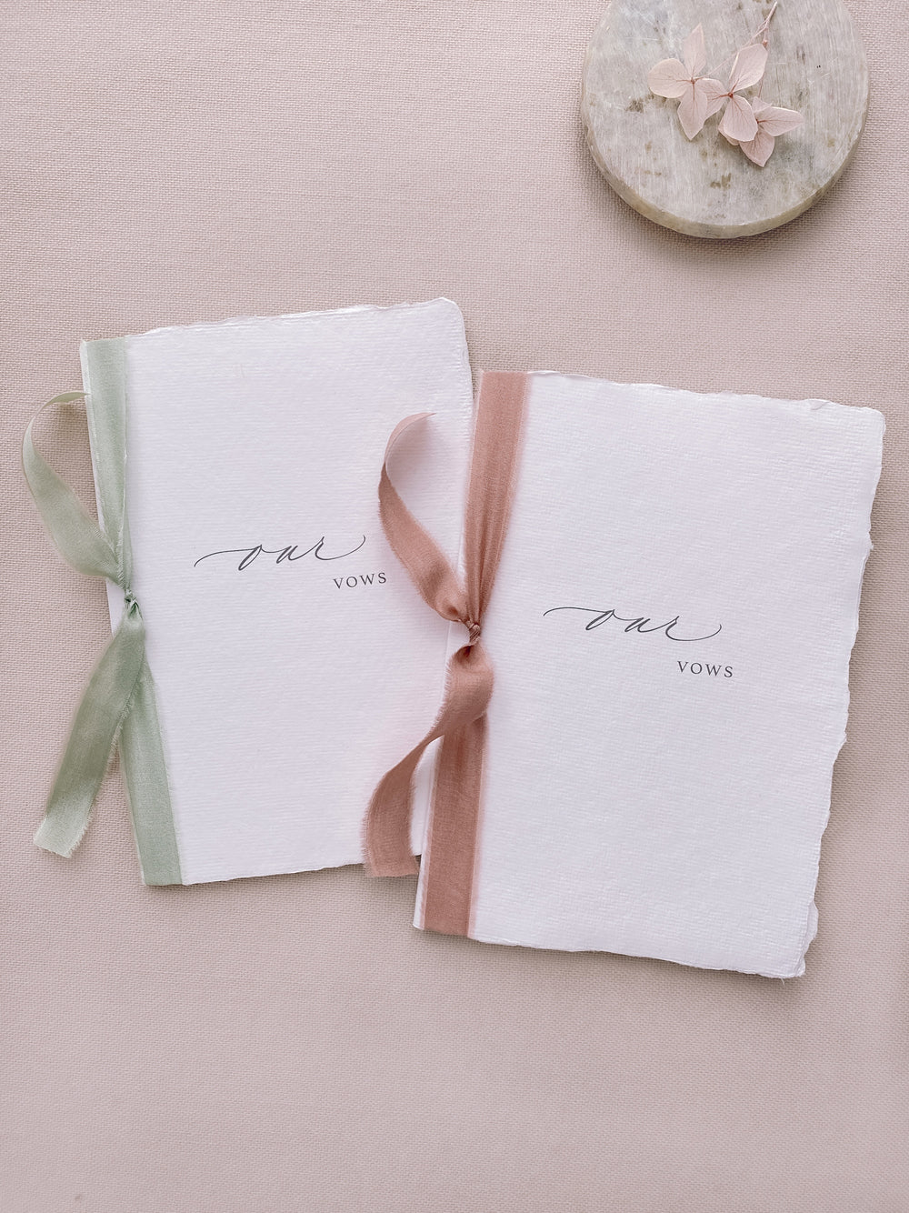 our vows white handmade paper vow books tied in sage green and rose colored silk ribbons