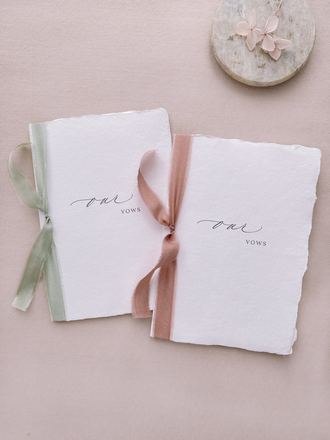 our vows white handmade paper vow books tied in sage green and rose colored silk ribbons