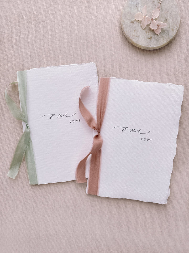 our vows white handmade paper vow books tied in sage green and rose colored silk ribbons