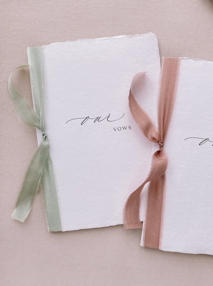 our vows white handmade paper vow books tied in sage green and rose colored silk ribbons