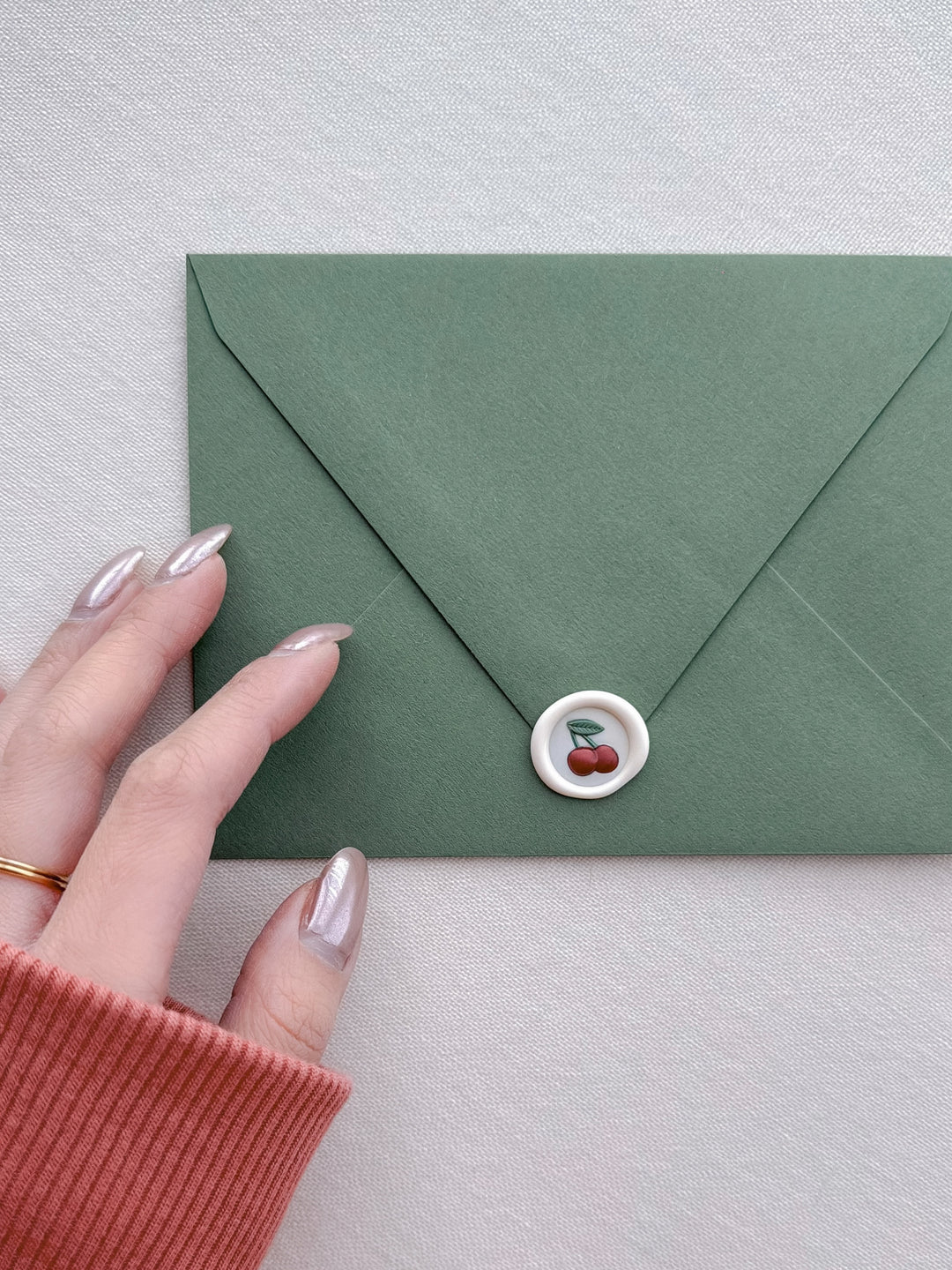 mini cherry emoji wax seal on a green envelope