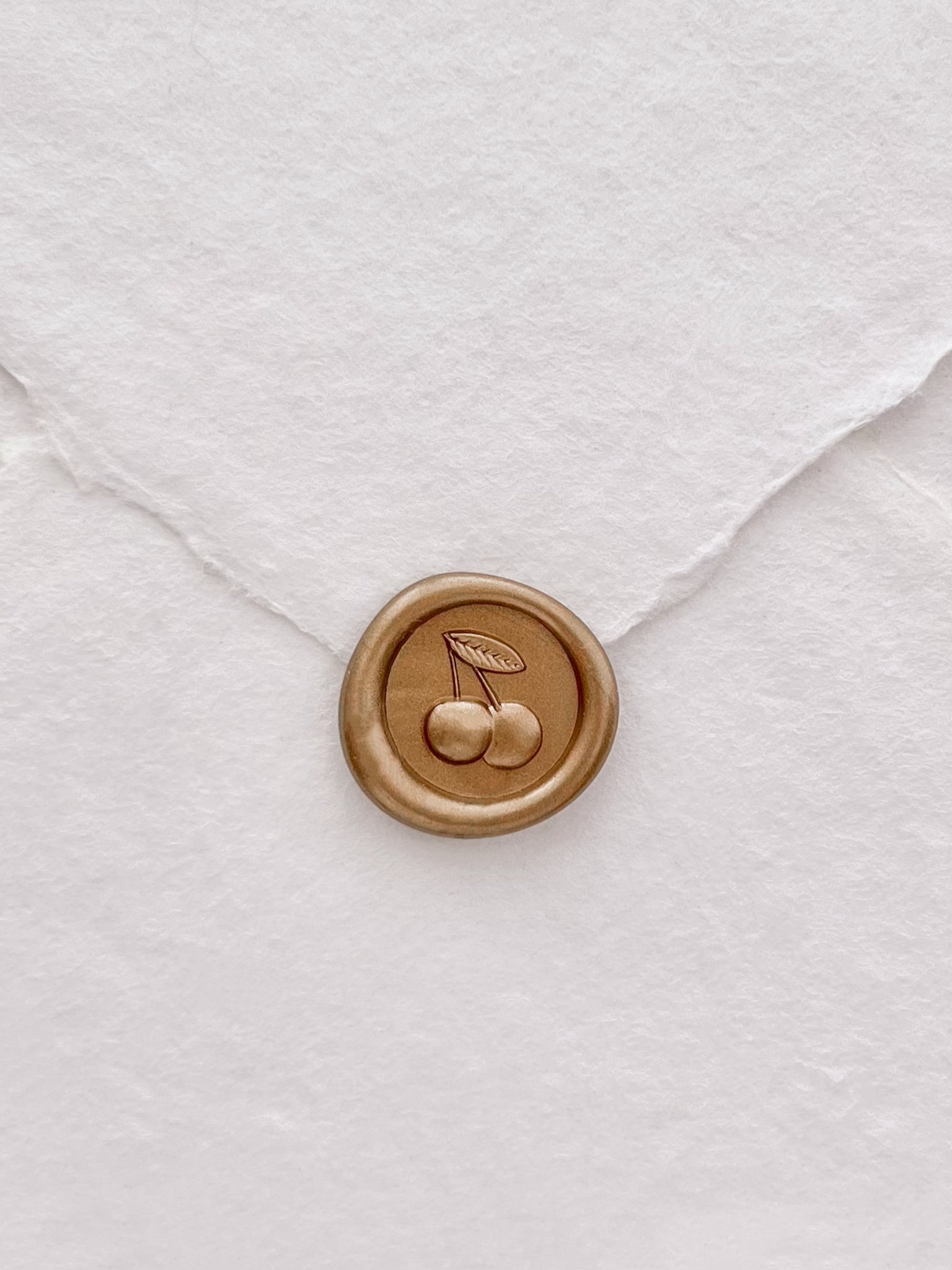 cherry emoji gold wax seal on a white handmade paper envelope