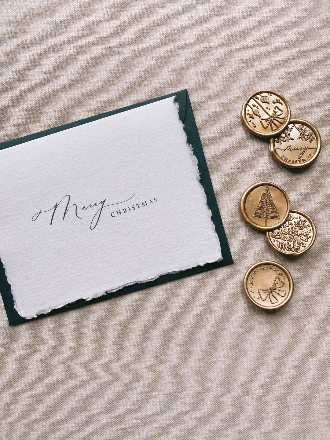 Merry Christmas handmade Christmas cards with deep green envelope with assorted designs of christmas ornaments, merry christmas, christmas tree, winter garden and ribbon bow Christmas wax seals in gold beside the card