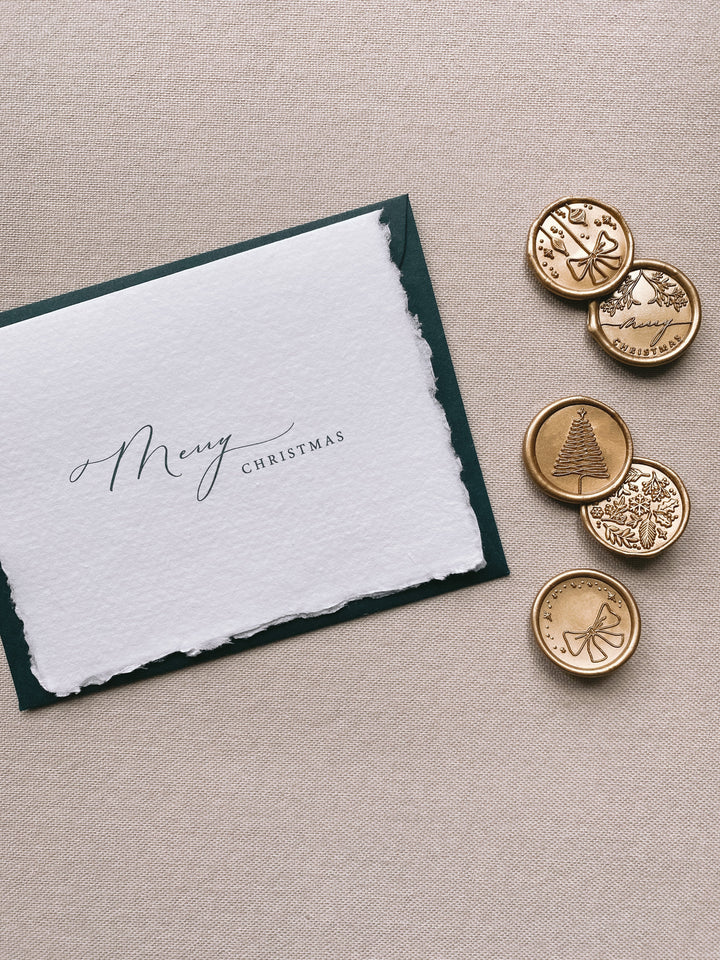 Merry Christmas handmade Christmas cards with deep green envelope with assorted designs of christmas ornaments, merry christmas, christmas tree, winter garden and ribbon bow Christmas wax seals in gold beside the card