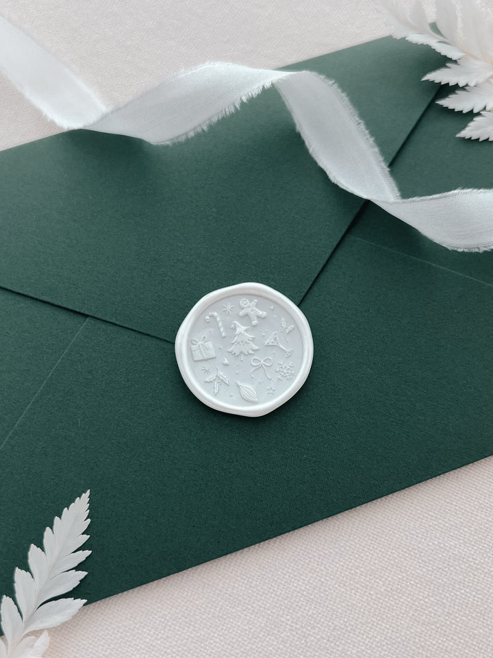 Pearl white Christmas wax seal featuring a design of festive icons such as gingerbread man, candy cane, snowflake, Christmas tree and more