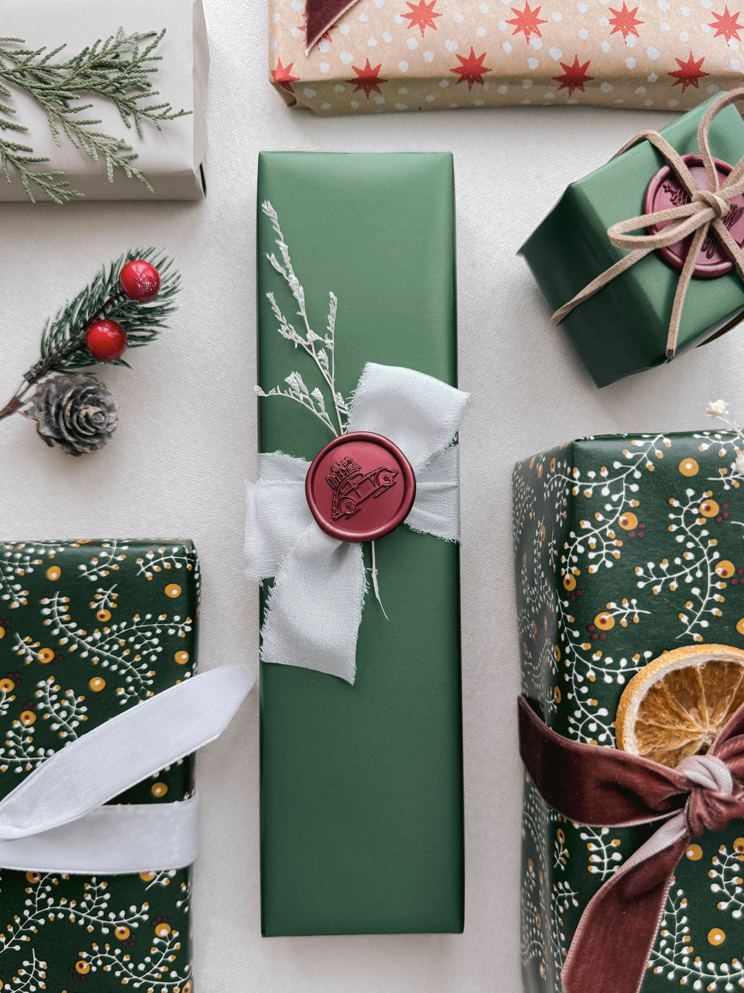 Dark metallic red festive wax seal with a  design of Christmas car and gifts, on a wrapped Christmas gift