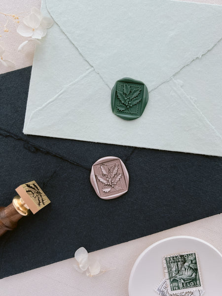 dark green and light bronze holiday holly leaf wax seals on sage green and black envelopes