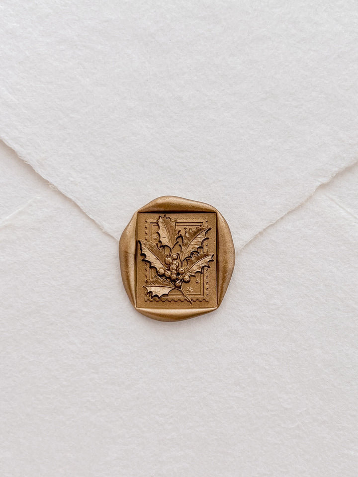 Gold Christmas holly and berries square wax seal on a white handmade paper envelope