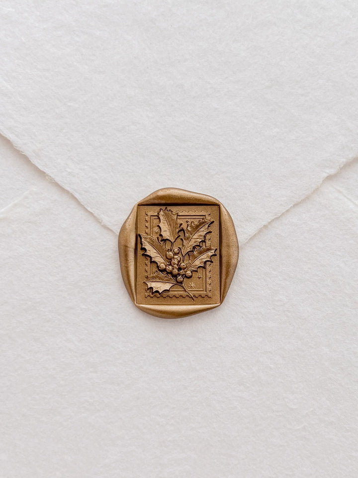 gold Christmas holly leaf wax seal on a white envelope