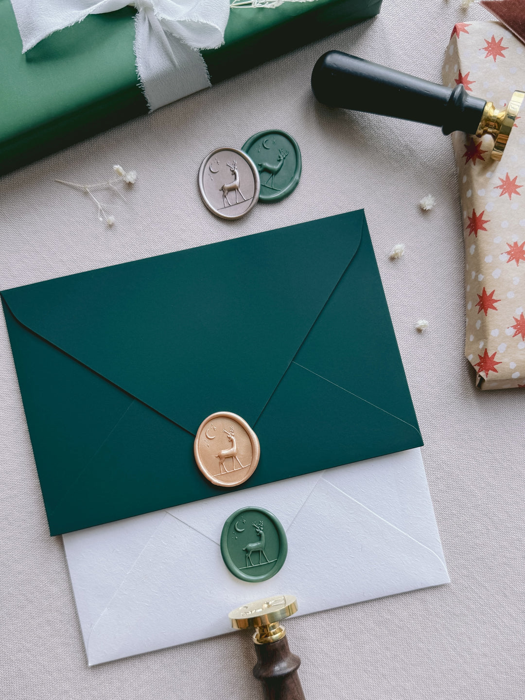 Peachy gold and sage green 3D reindeer oval wax seals on Christmas card envelopes