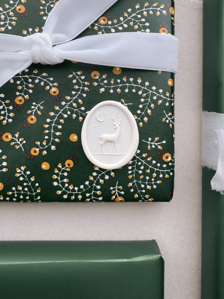 Antique white 3D reindeer oval wax seal on a christmas gift with a festive-designed wrapper.