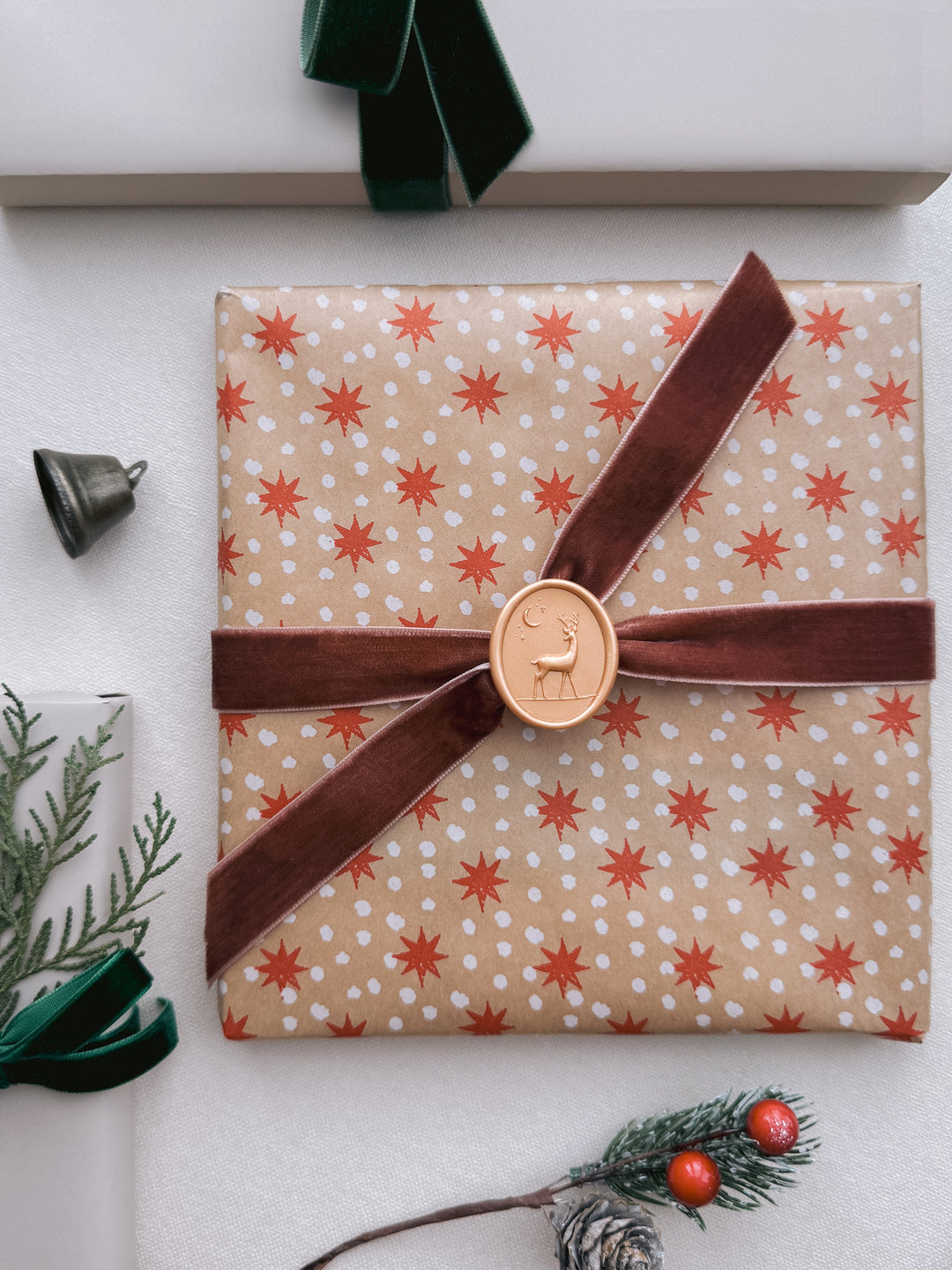 Light gold colored oval 3D reindeer wax seal on a wrapped Christmas gift