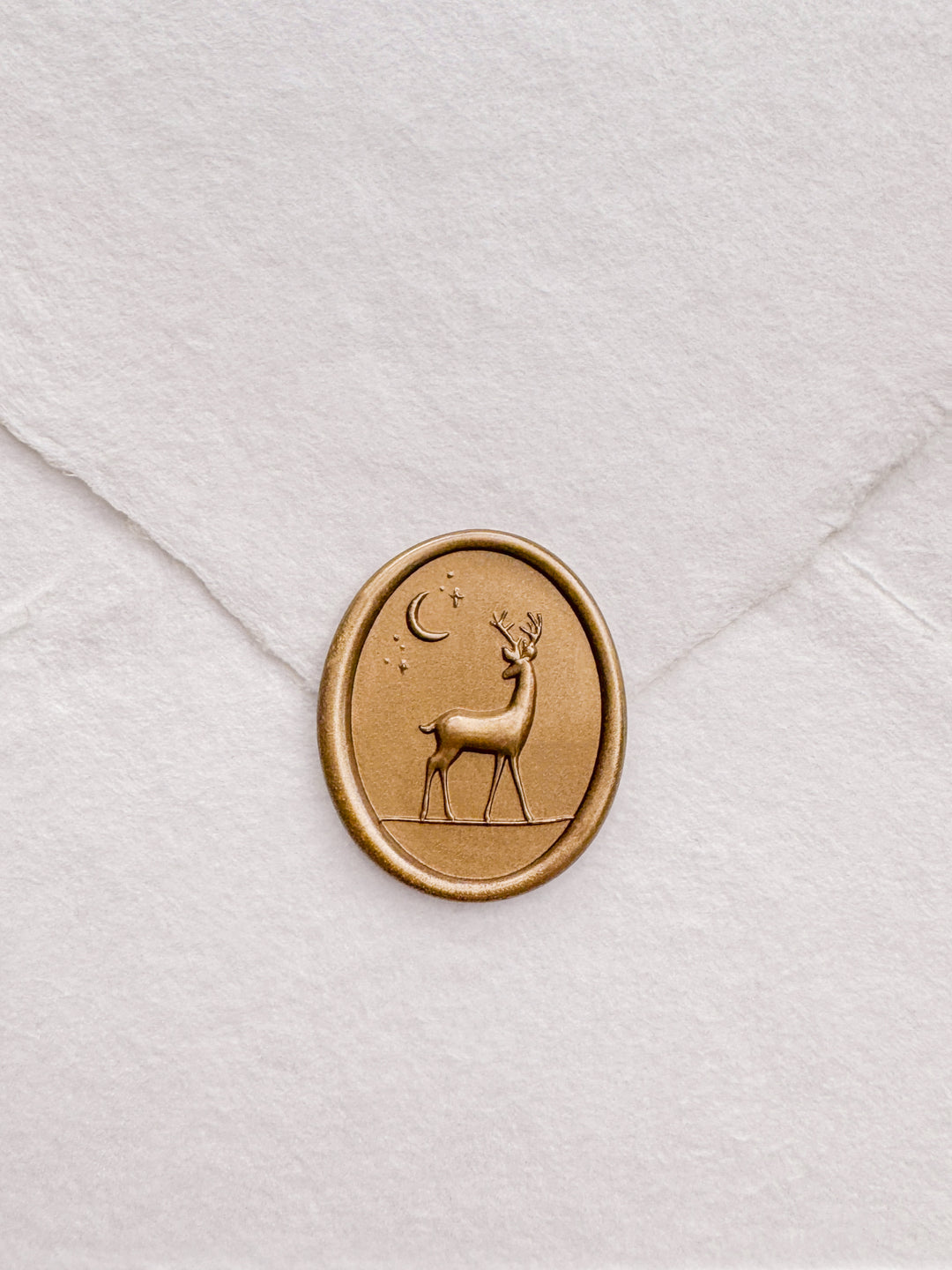 Gold 3D reindeer oval wax seal on a white deckled edge handmade paper envelope 