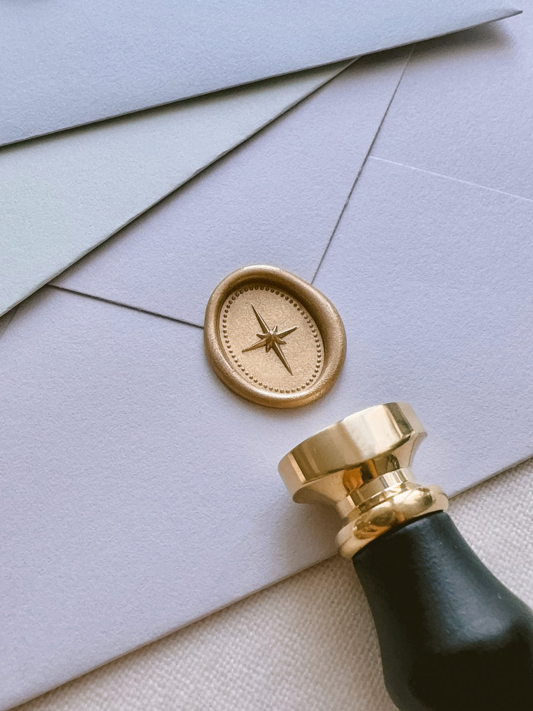 light gold North Star mini oval wax seal on a light purple envelope