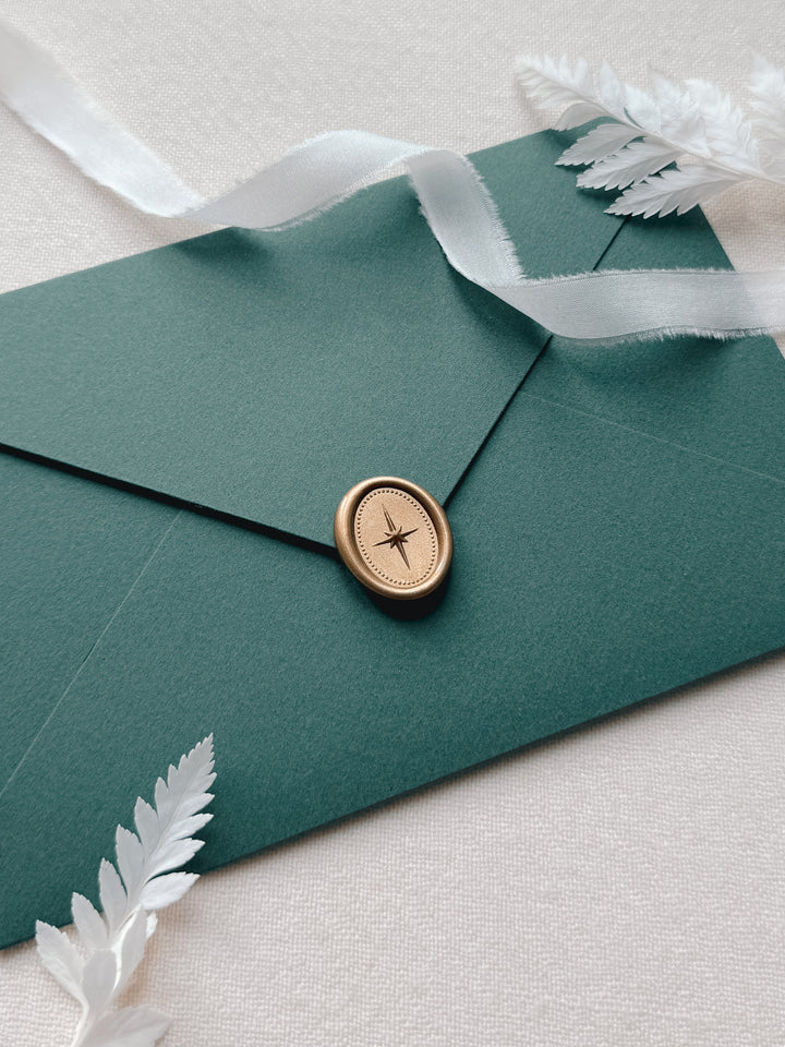 Gold mini oval North Star wax seal on a dark green Christmas card envelope