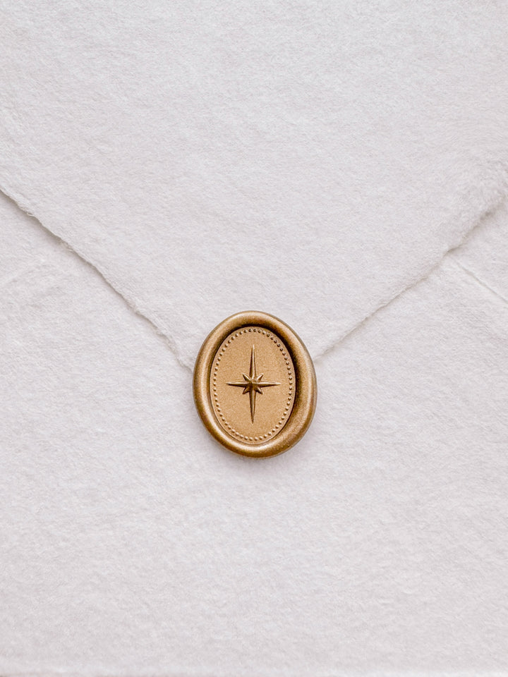Gold mini oval 3D North star wax seal on a  white deckle-edge handmade paper envelope
