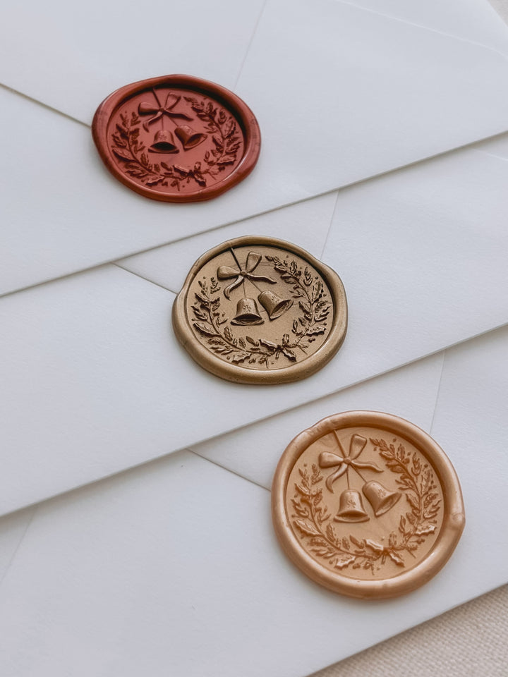 Dark metallic red, gold, and orange gold Christmas wreath and jingle bells wax seals with 3D engraving on white envelopes
