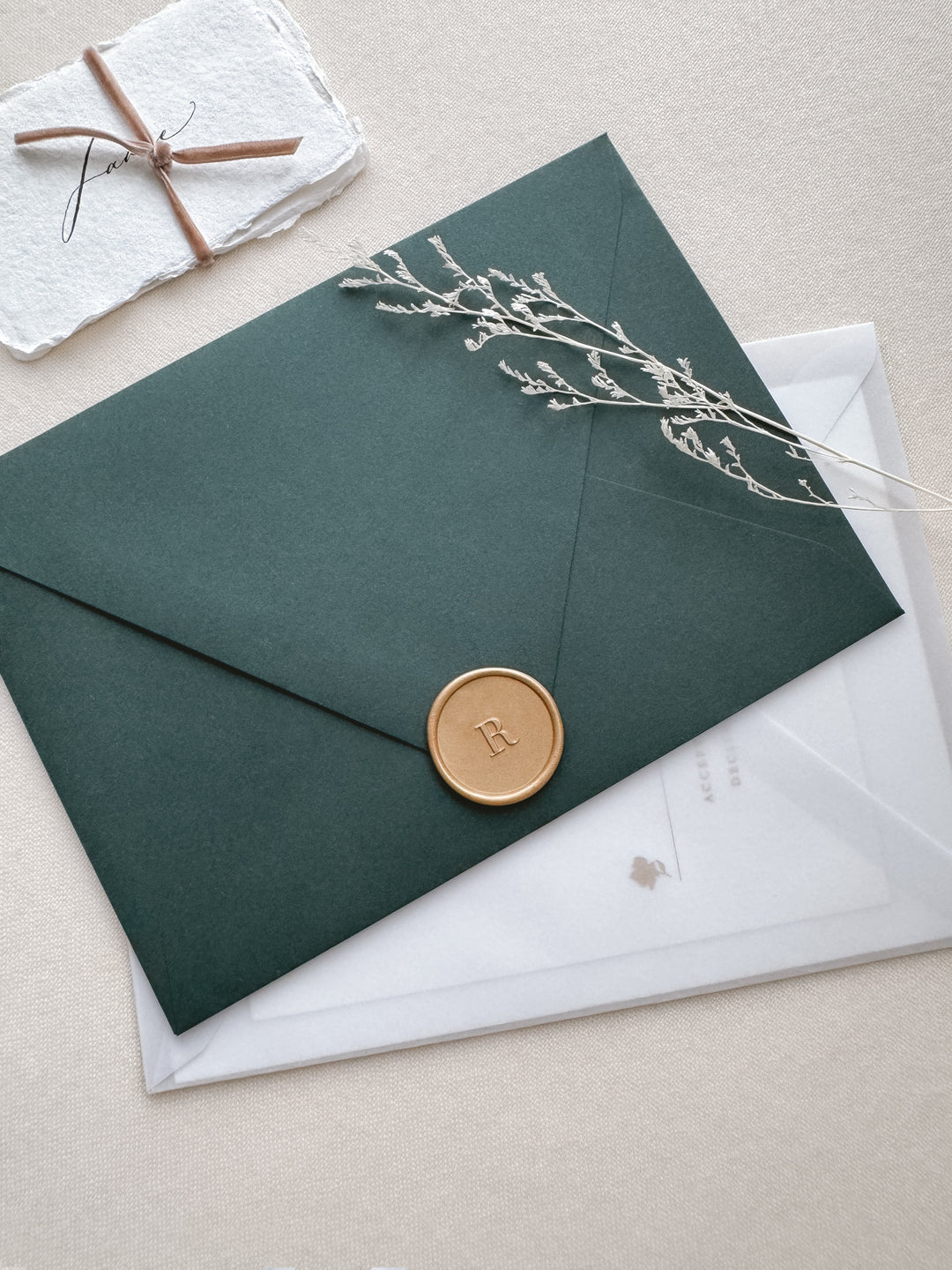 light gold personalized letter wax seal on a dark green envelope