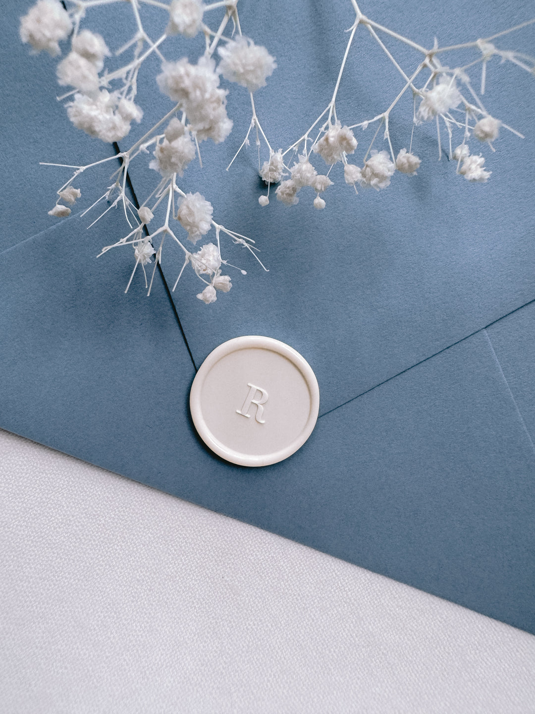 off-white customer letter wax seal on a dusty blue envelope