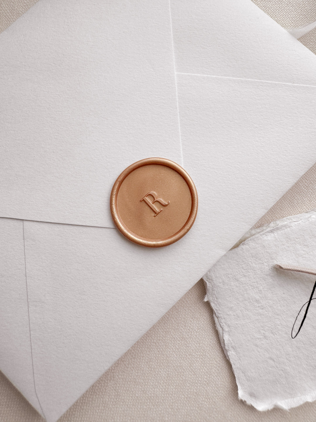peachy gold custom initial wax seal on a white envelope