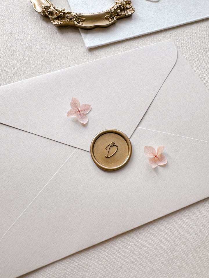 calligraphy script custom initial gold wax seal on a beige envelope