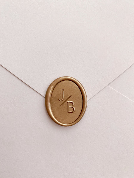 Oval monogram custom wax seal in gold on beige paper envelope