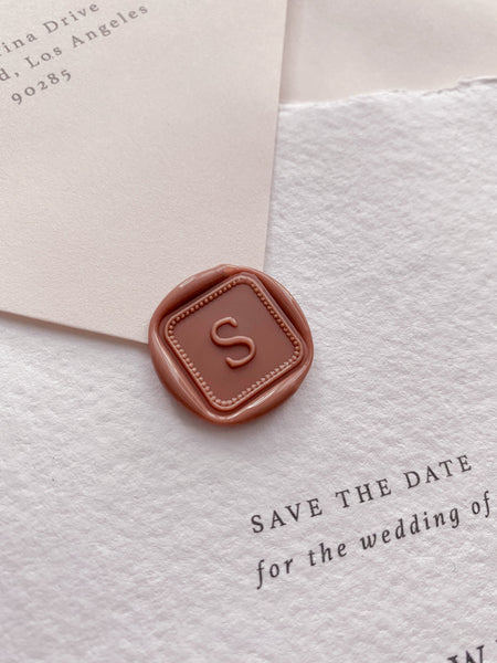 Single initial with border design mini square dusty rose custom wax seal on beige paper envelope with Save the Date card