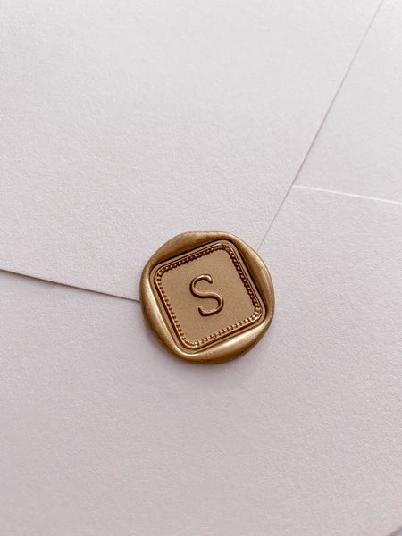 Single initial with border design mini square gold custom wax seal on beige paper envelope