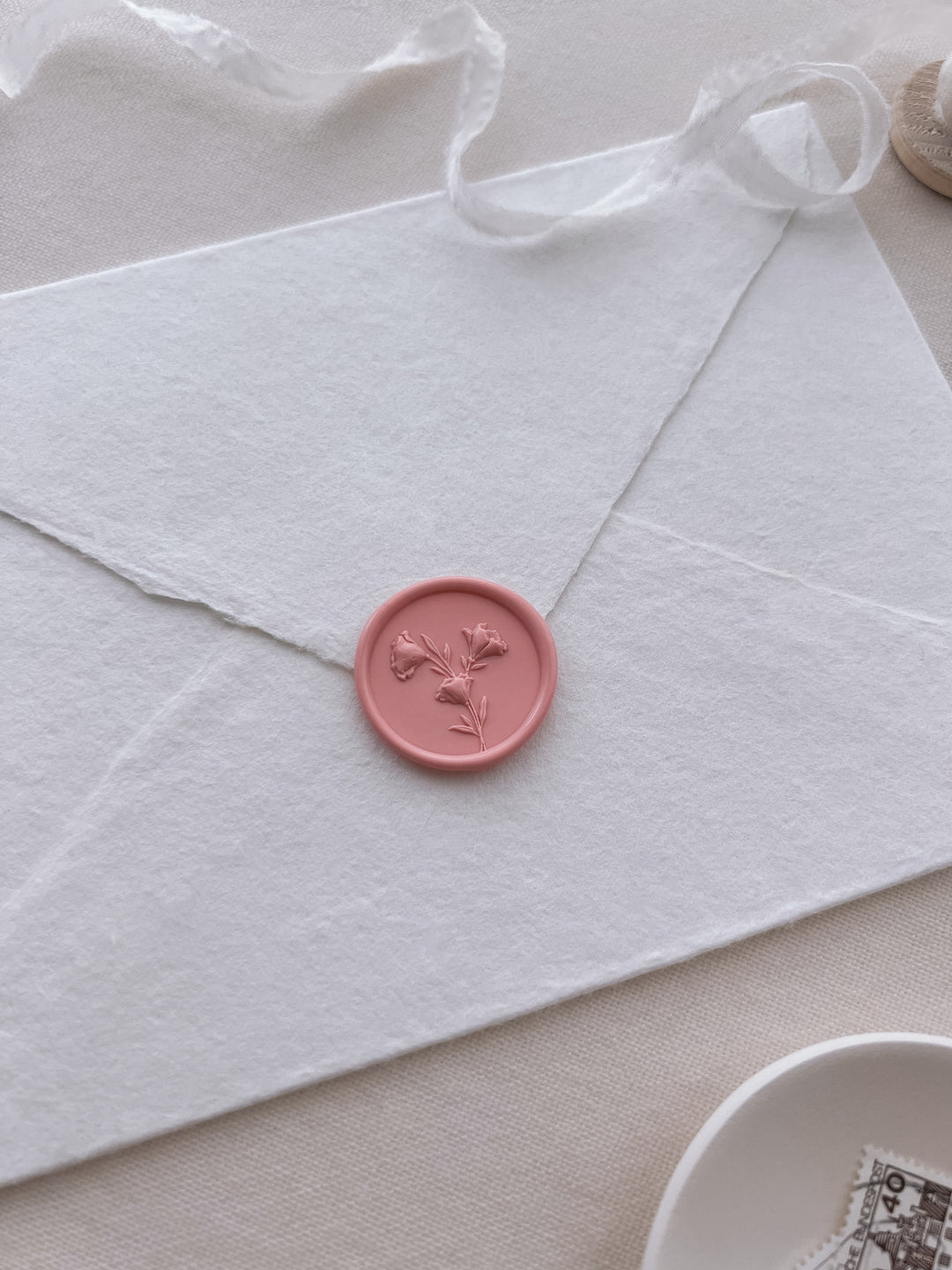 coral pinkish orange 3D flower design wax seal on a white envelope
