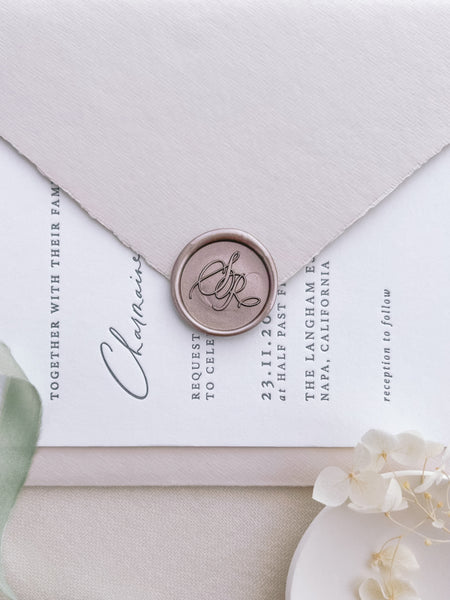 Light bronze custom script monogram wax seal on wedding invitation card and beige envelope
