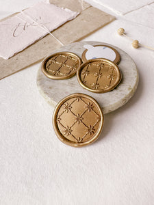 Daisies symmetrical pattern gold wax seals styled with a small gray stone dish, handmade paper and a dried floral branch