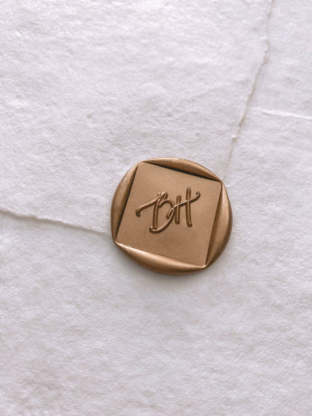 Calligraphy script monogram diamond shaped wax seal in gold handmade paper envelope_side angle