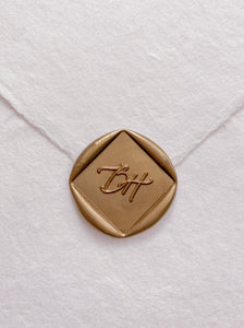 Calligraphy script monogram diamond shaped gold custom wax seal on beige handmade paper envelope