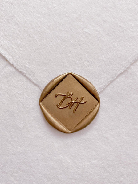 Calligraphy script monogram diamond shaped gold custom wax seal on beige handmade paper envelope