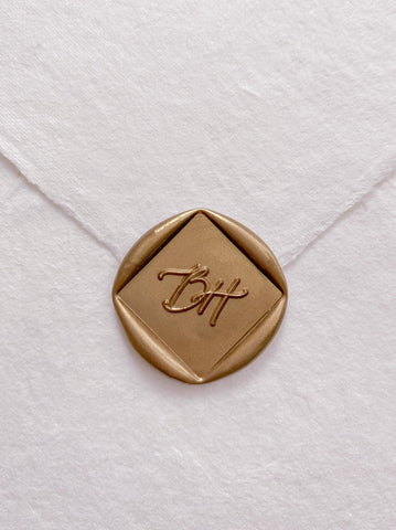 Calligraphy script monogram diamond shaped gold custom wax seal on beige handmade paper envelope