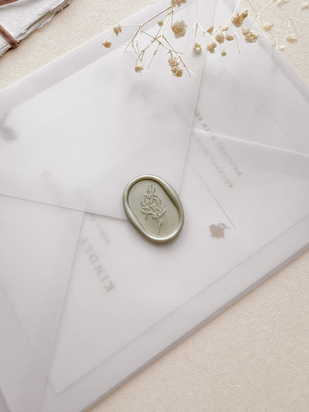 Oval arch shaped leaf design wax seal in a light sage color on a vellum wedding invitation envleope