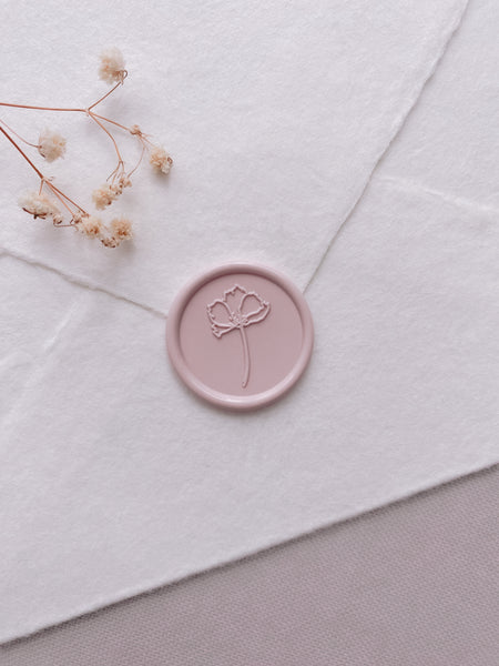dusty nude colored round flower wax seal on white handmade paper envelope