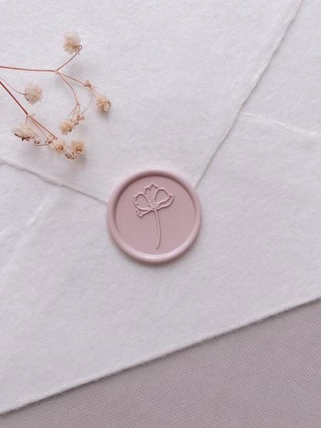 Light pink simple flower round wax seal on white handmade paper envelope styled with dried flowers 