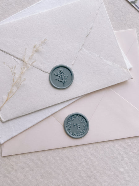 teal colored eucalyptus bouquet wax seal and custom monogram wax seal on white and beige envelopes
