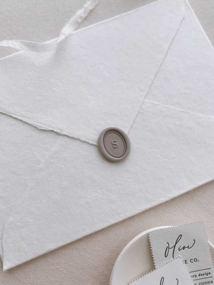 soft taupe colored personalized initial oval wax seal on a white envelope