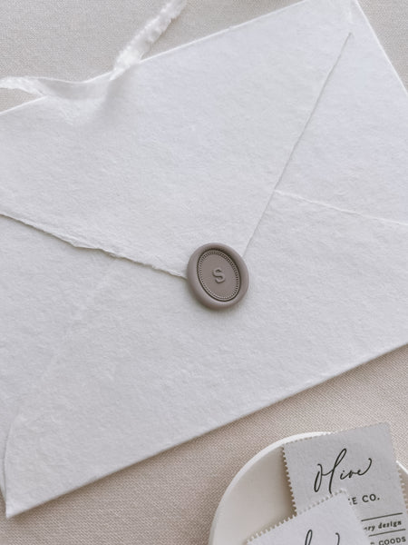 soft taupe colored personalized initial oval wax seal on a white envelope