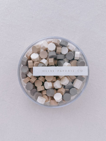 assorted color mix of sealing wax beads in a clear container box, with white, beige and taupe wax beads