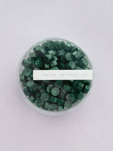 metallic green sealing wax beads in a clear round container